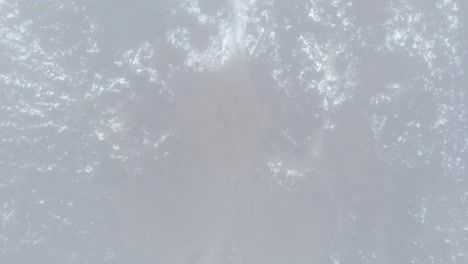 descendiendo aéreo de arriba hacia abajo revela de otoño hojas coloridas de la copa de los árboles en el paisaje de páramo visto a través de un espeso fondo de niebla húmeda misteriosa y nieve esparcida alrededor de la escena de invierno