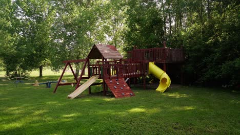 wide push in shot of a kids jungle gym and swing set with slides and swings in the front yard of a home