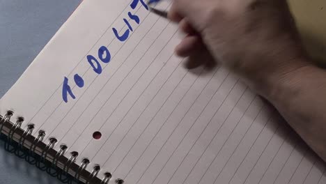 mano della persona occupata che scrive una lista di cose da fare sul blocco note