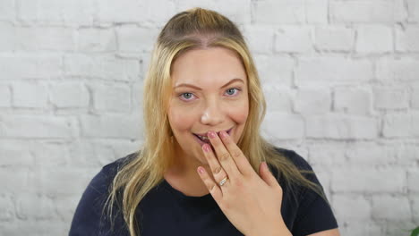 a surprised and shocked happy blonde woman holding hand to mouth and embarrassed