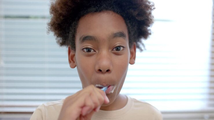 Portrait of african american boy brushing teeth in bathroom, slow motion