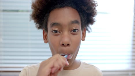 portrait of african american boy brushing teeth in bathroom, slow motion