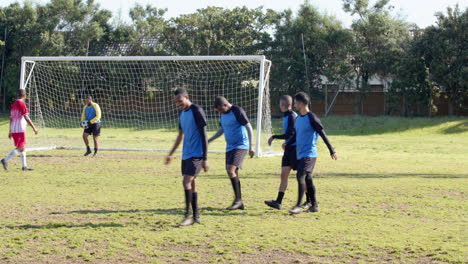 soccer players walking off field after match near goalpost on sunny day