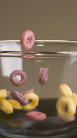 pouring colorful ring cereal into a glass bowl