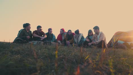 tourists talk sitting at burning bonfire in autumn evening