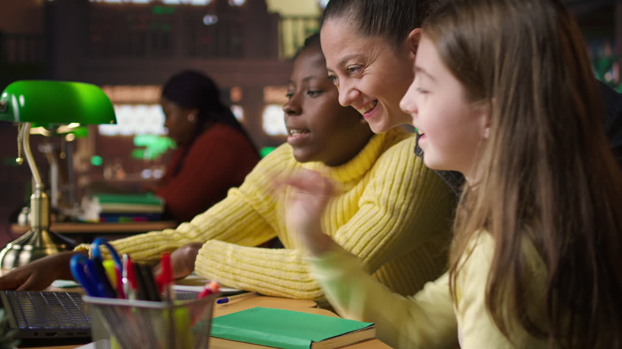 Teacher helping students with laptop in class
