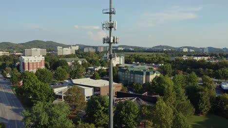 aerial rising to reveal cell phone 5g communication tower in busy area, 4k