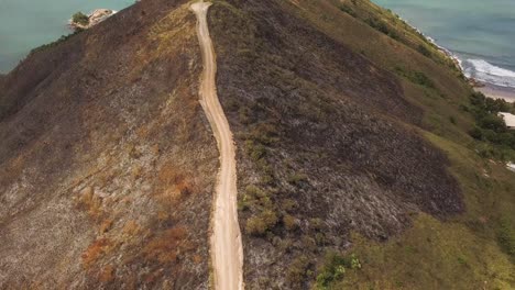 inclinación aérea hacia abajo de la carretera de tierra en la cima de la montaña con vegetación quemada por el fuego