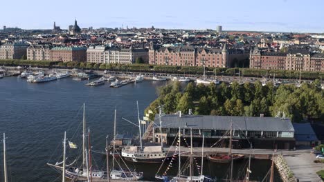 Veleros-En-El-Muelle-Con-El-Horizonte-De-La-Ciudad-Al-Fondo-Durante-La-Tarde-Soleada-En-Djurgården,-Estocolmo,-Suecia