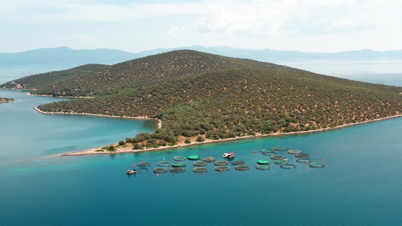 Fish farm by sea in Greece. Fish breeders in natural marine waters. View island in sea. Aerial view of slide from drone on beautiful panorama of sea and mountains on island.  Seafood. Travel. Tourism