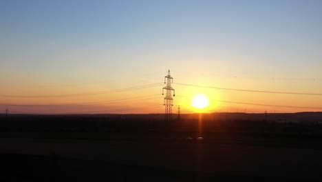 Golden-Hour-Sunset-With-Electricity-Pylon-In-Silhouette-Against-Sunlit-Background