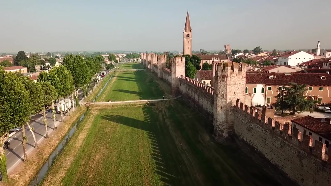 Vista aérea de Montagnana, no Vêneto, com as longas muralhas medievais, telhados de terracota e o alto campanário da igreja elevando-se sobre a cidade.