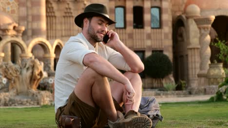 turista hablando por teléfono mientras está sentado en la mezquita de hierba, india