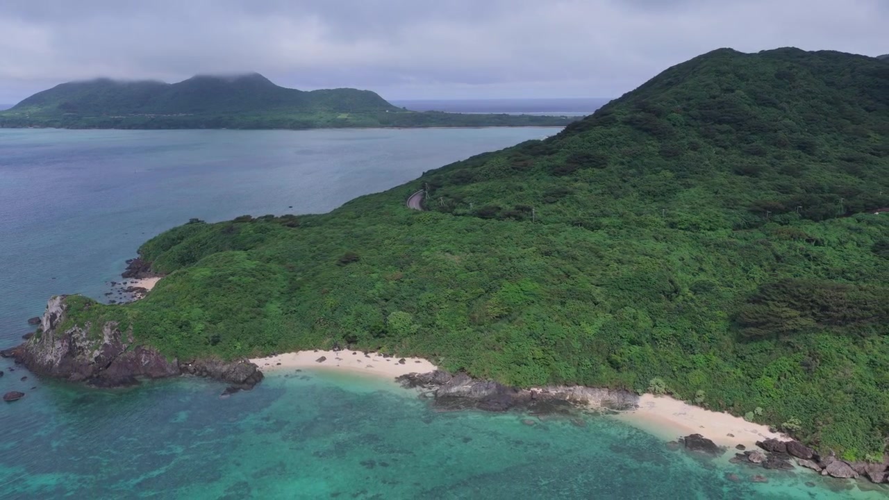 Japonya, Okinawa, Ishigaki Adası'ndaki Nosokoniaru Plajı ve Ibaruma Koyu'nun beyaz kumlu koyu ve yemyeşil sahil şeridi üzerinde geriye doğru kayan yatay havadan çekim.