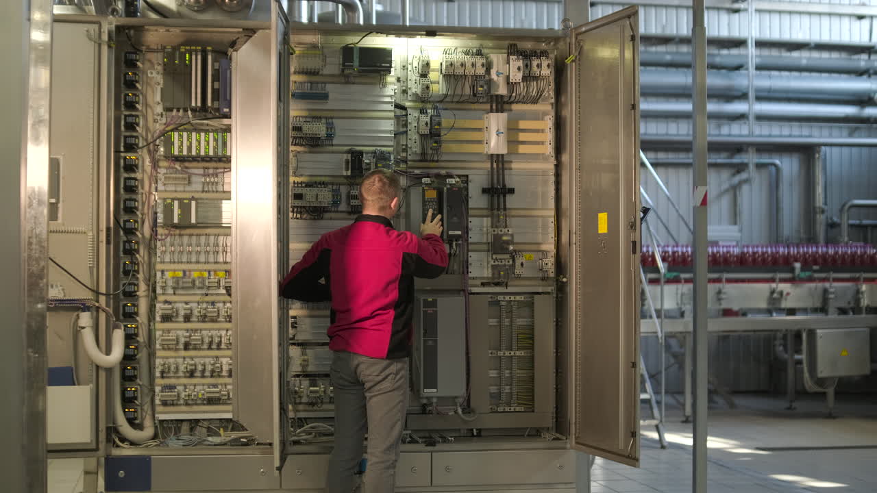 Engineer Working on Electrical Control Panel in Industrial Factory