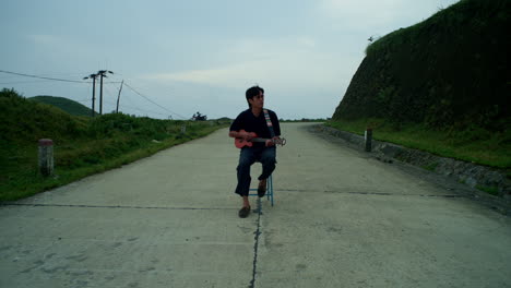 musician playing the ukulele in the middle of the road