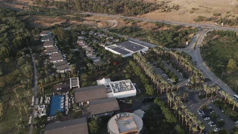 Aerial-overview-of-hotel-complex,-surrounded-by-barren-landscape,-golden-hour