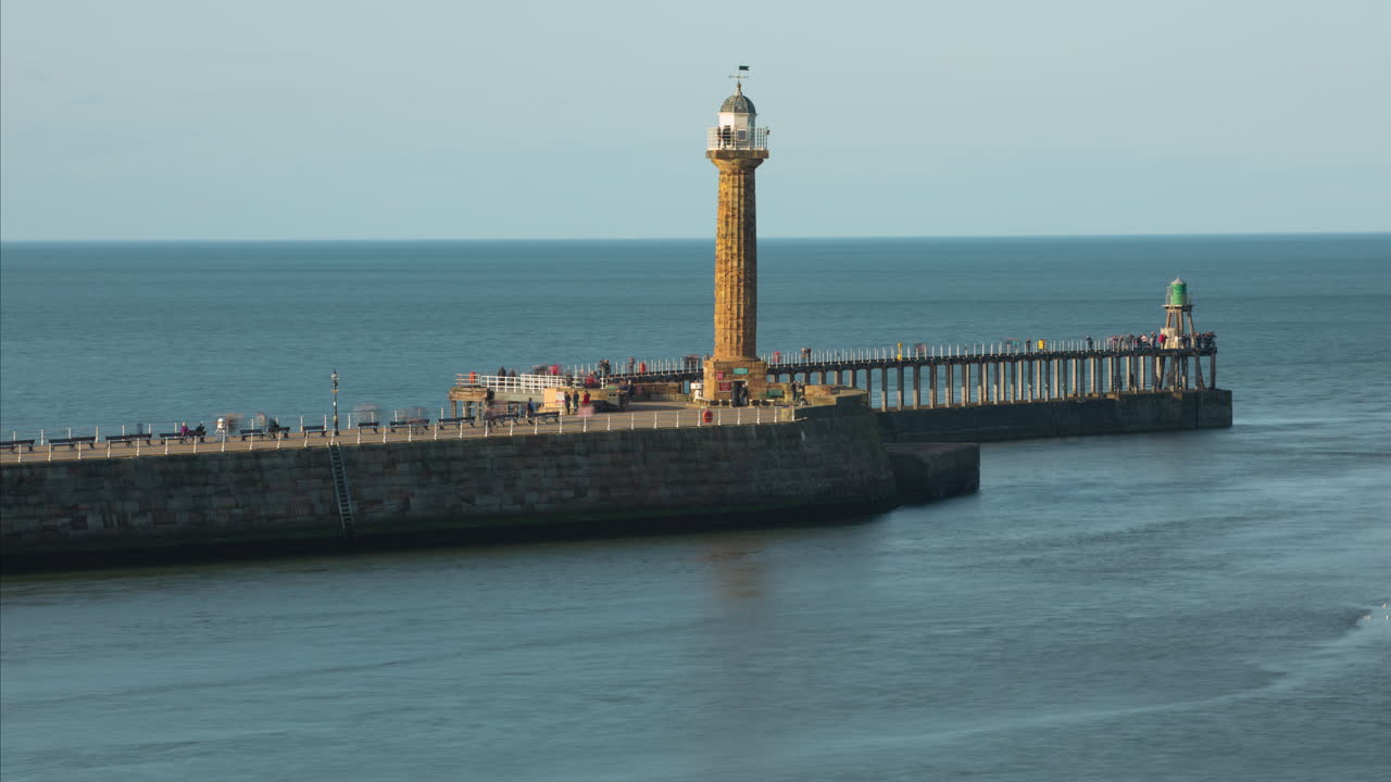 부두에 많은 관광객과 유람선이 지나가는 휘트비 부두 저녁 햇살