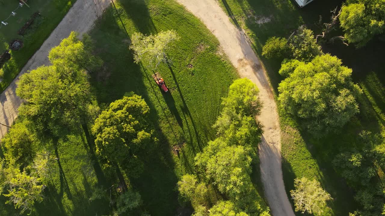 antena de arriba hacia abajo del tractor rojo cortando hierba verde en el parque durante la puesta de sol -uruguay, américa del sur