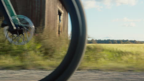 gravel bike front wheel appears from the left when driving through grain fields and passing an old barn