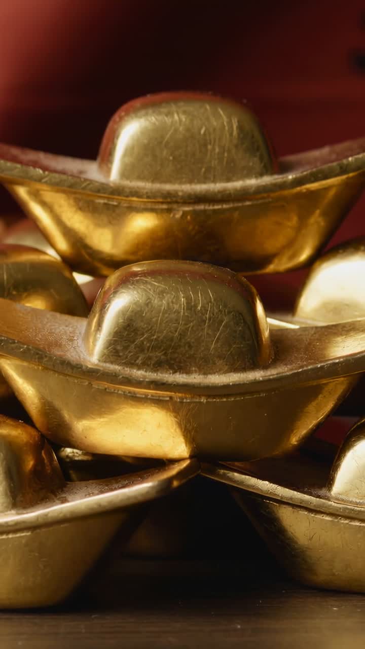 Video verticale: lingotto d'oro su barca che luccica mentre la calda luce della lampada si sposta sulla base scura, mostrando segni di usura