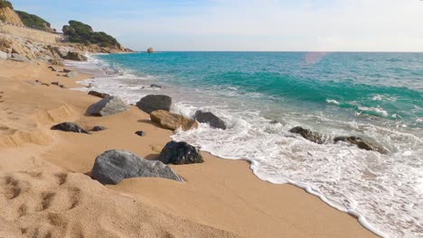 Hermosa-Playa-De-Arena-Mediterránea,-Maresme-Barcelona,-San-Pol-De-Mar,-Con-Rocas-Y-Mar-Tranquilo-Y-Turquesa,-Costa-Brava,-Calella-De-Mar