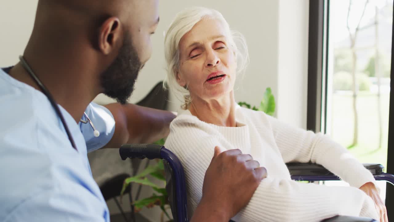 Video of happy african american male doctor taking care of caucasian senior woman