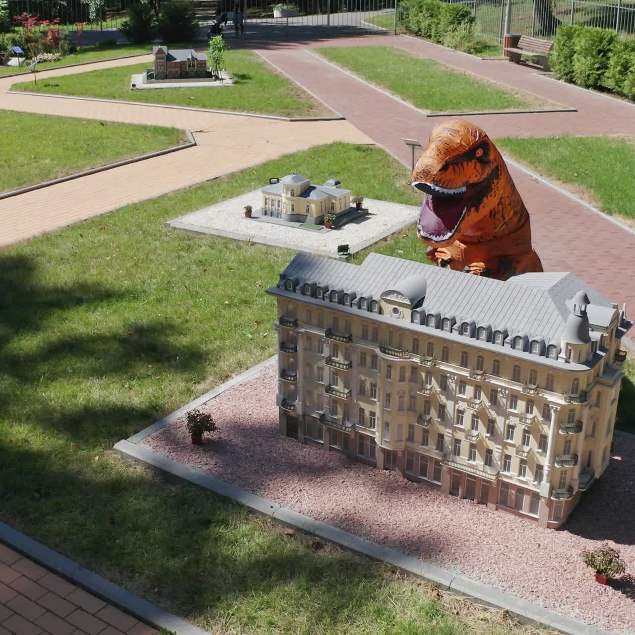 Dinosaur opened his mouth widely standing behind the little building. Tirex dinosaur towering above the house. Top view