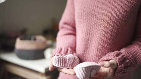 female hands holding baby booties. knitted shoes handmade for children