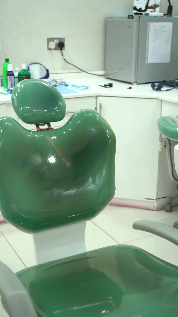 Panoramica su una sala per esami dentali professionale con poltrona verde per il paziente, sputacchiera e armadietti bianchi sterili