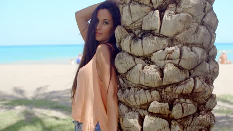 Pretty-Woman-Leaning-Against-Beach-Palm-Tree-Trunk