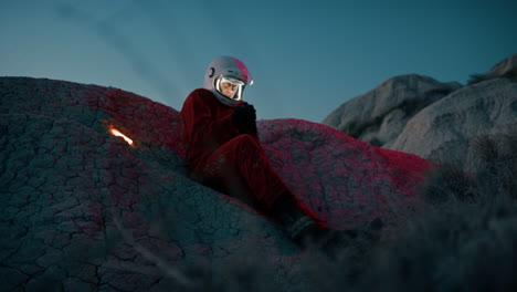 cold lonely astronaut on a mountain at night with helmet preparing to sleep