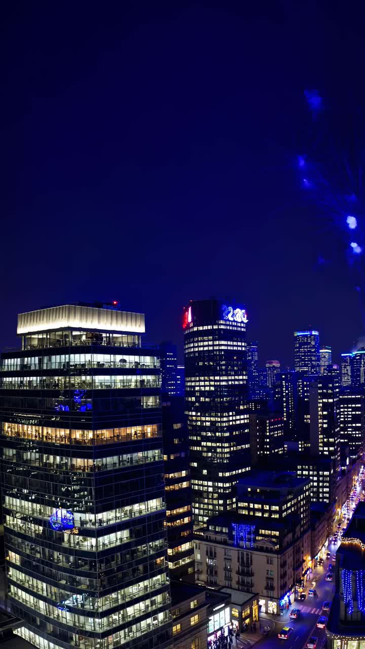 Aerial view of a city skyline at night with vibrant fireworks. The video captures the dynamic urban