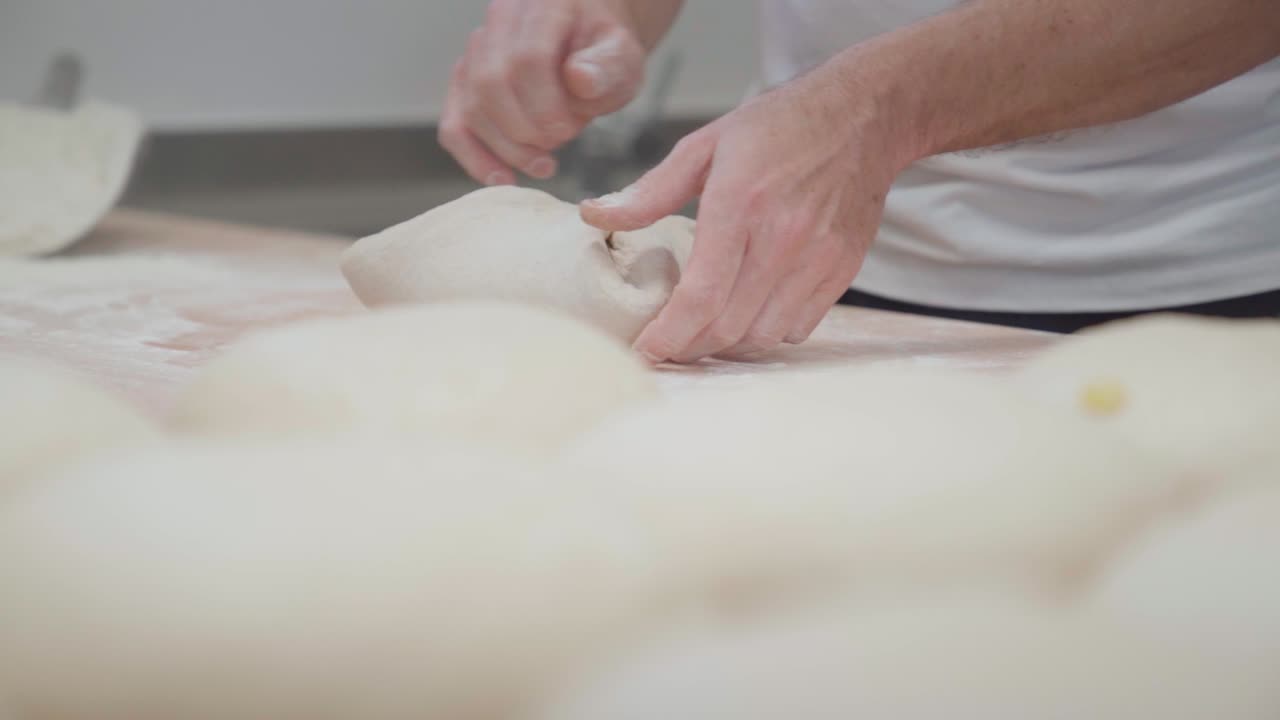 Bager der forbereder et brød i et bageri ved hjælp af en dejspatel