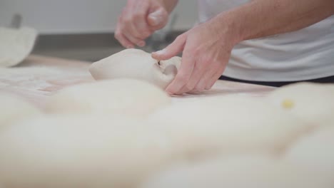 baker preparing bread loaf in bakery using dough scraper