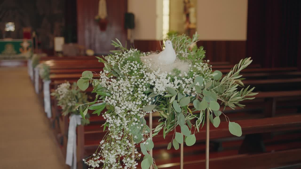 Verde e fiori bianchi disposti sui banchi della chiesa lungo la navata