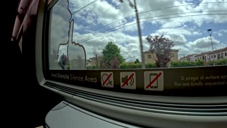 hyperlapse view looking out of the window of a train travelling on the outskirts of a city in an empty frecciarossa business class carriage, italy