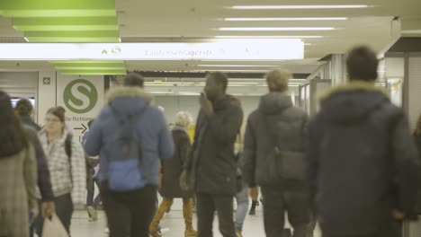 people walk through a busy underground corridor with fluorescent lights and blurred motion