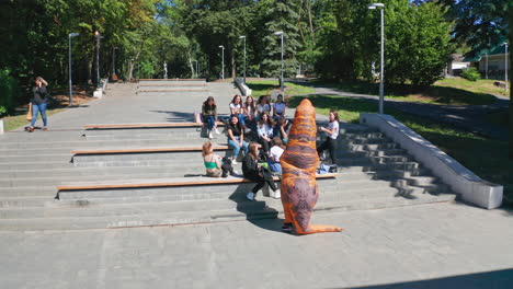 teenagers gather around a dinosaur costume in a park