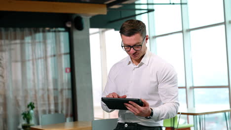 using digital technology in modern business. man in glasses works on his i-pad in a spacious office.