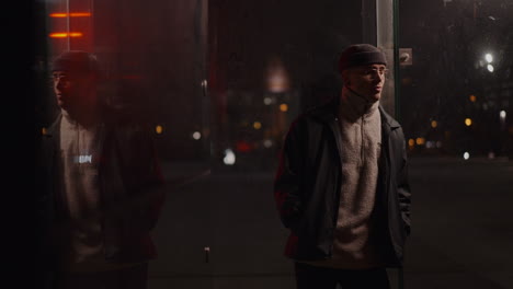 man in beanie and glasses reflects at night in an urban setting