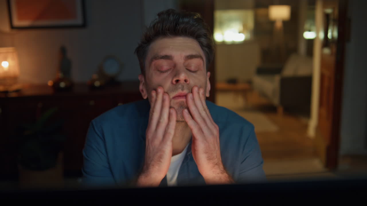 Exhausted man rubbing temples working at night flat closeup. Tired freelancer