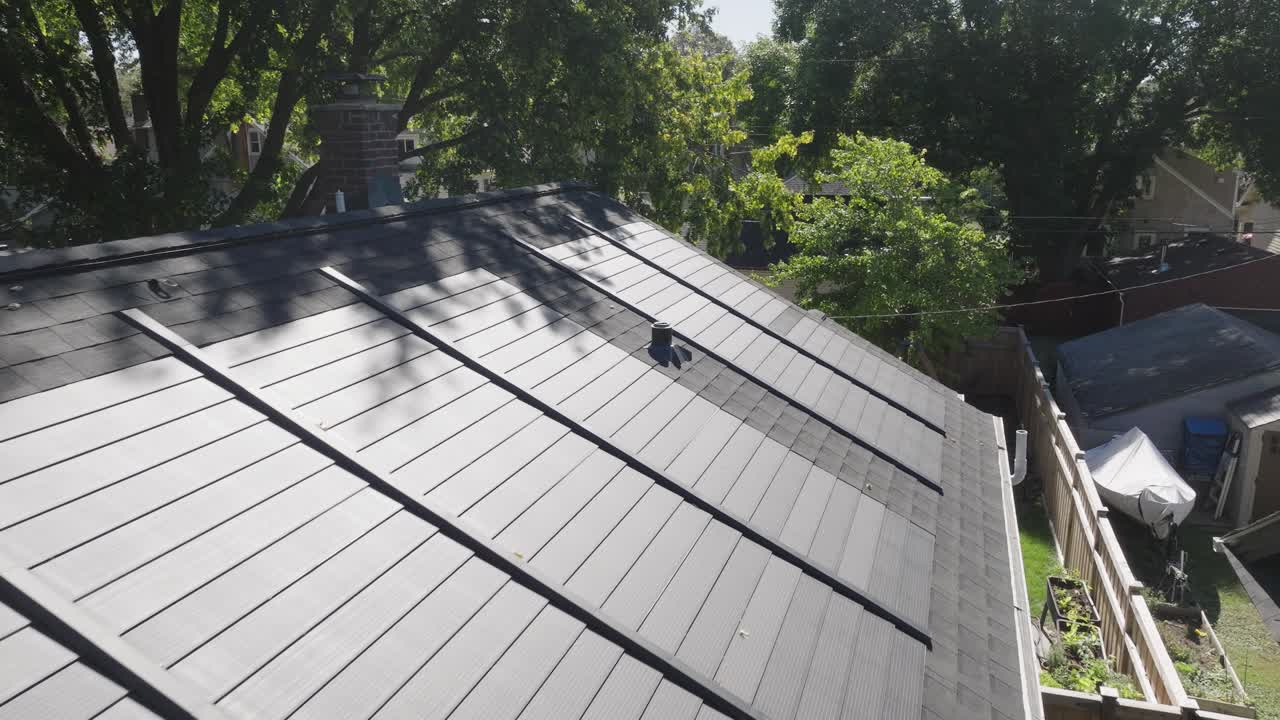 vista de avión no tripulado de tejas solares en un techo residencial rodeado de árboles.