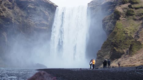 tourist attraction skogafoss waterfall in iceland with people walking around