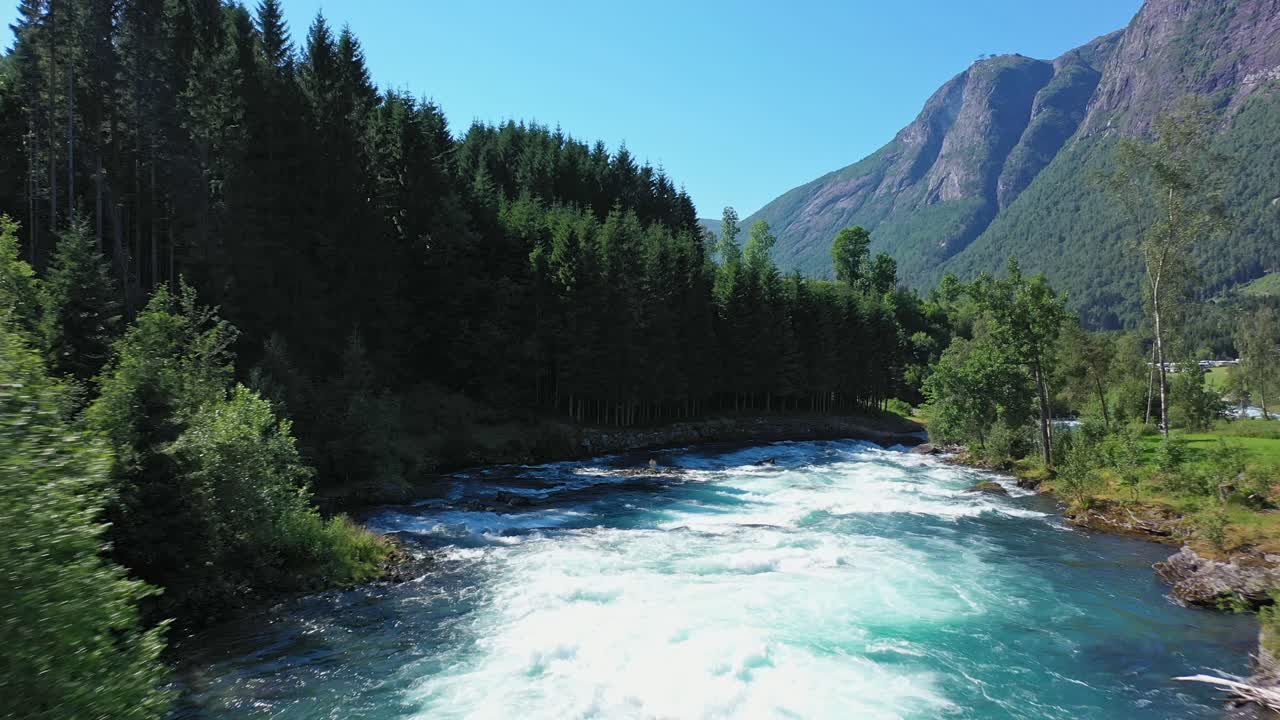 Stor turkis krystallklar breelv som renner ned fra Lovatnet i Norge - Smeltet breis fra Jostedalsbreen til havet i frodige idylliske omgivelser - Fremoverbevegende luftfoto tett på elven