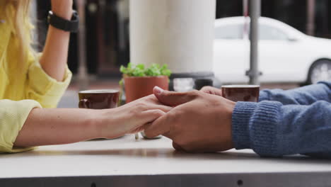 Focus-of-Caucasian-couple-holding-their-hands-at-terrace-coffee