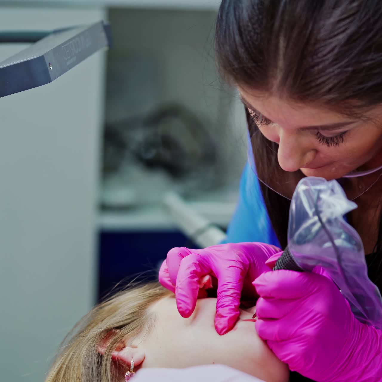 Beauty spa. Young cosmetologist doing permanent make-up tattoo on patient's lips. Professional tattooist making permanent make-up. Cosmetology concept.