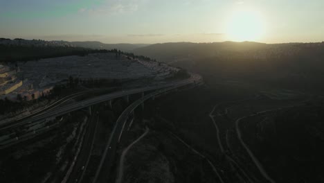 Toma-Aérea-De-Paralaje-De-La-Puesta-De-Sol-Sobre-El-Bosque-Y-La-Carretera