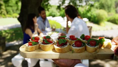 waiter serving appetizers to couples