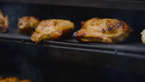 close up view of golden brown chicken pieces on bbq grill with smoke rising